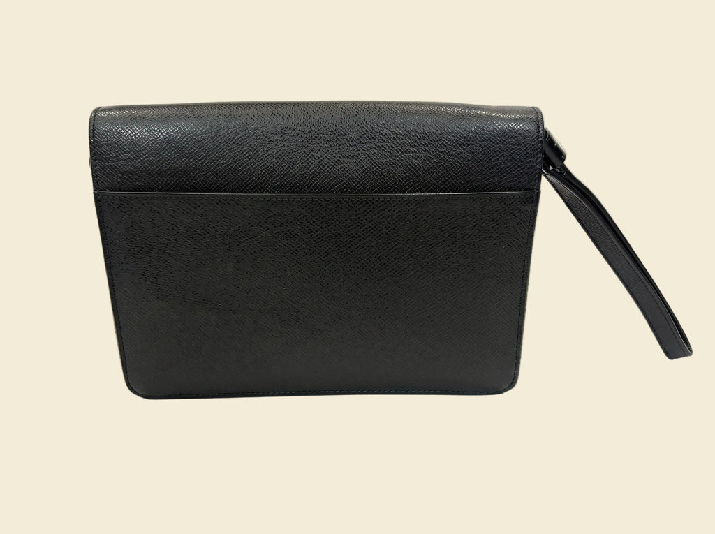 The Grand Tour Co. vintage Louis Vuitton Taiga leather Kourad wristlet clutch in dark green with a wrist strap.