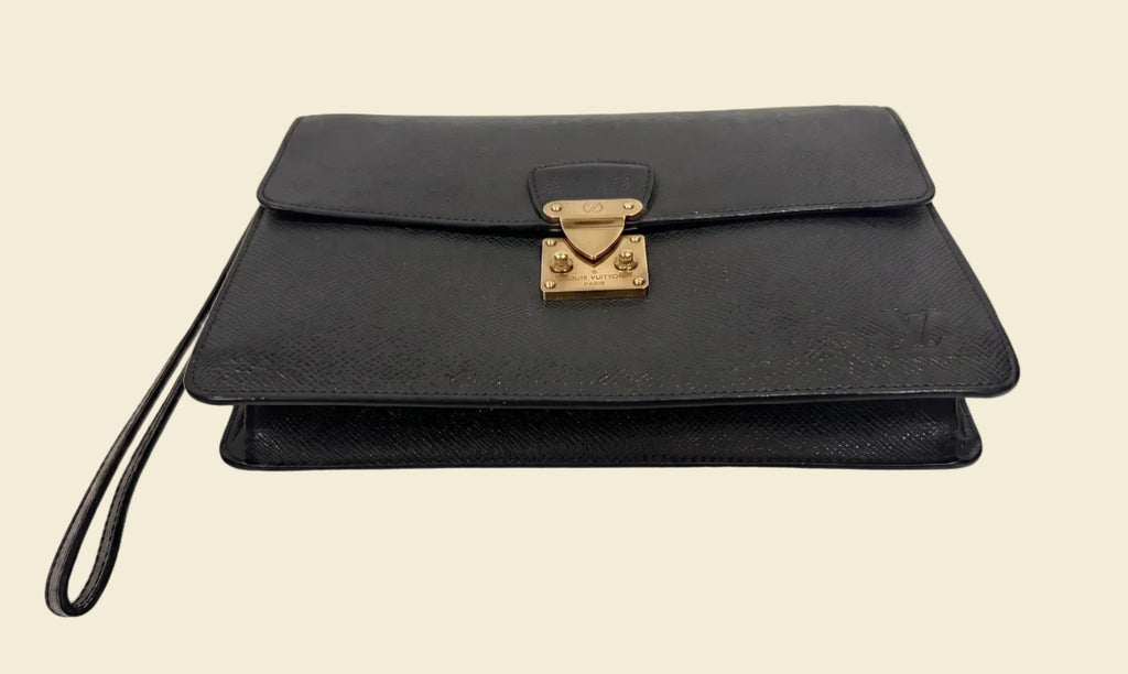 The Grand Tour Co. vintage Louis Vuitton Taiga leather Kourad wristlet clutch in dark green with gold-tone hardware.